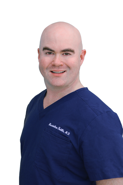 Dr. Maximilian Padilla in a navy blue scrubs. He is in his mid thirties, has a bright smile, kind eyes, and he is bald.