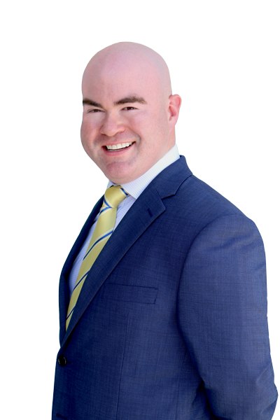 Dr. Maximilian Padilla in a navy blue suit with a blue and gold tie. He is in his mid thirties, has a bright smile, kind eyes, and he is bald.